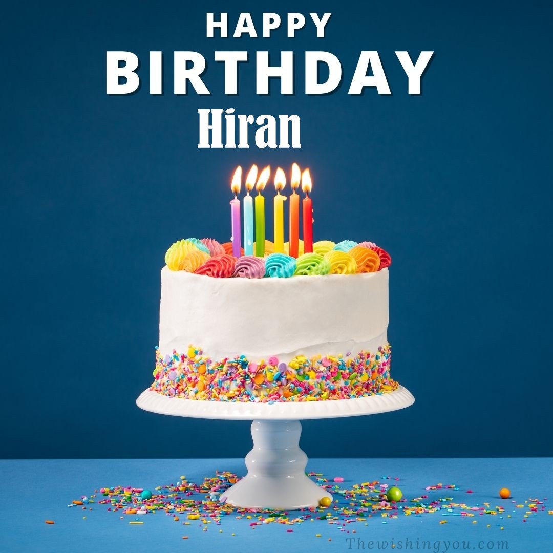 Happy birthday Hiran written on image White cake keep on White stand and burning candles Sky background